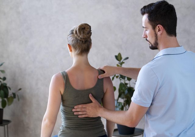 Physiotherapist examining patient's back for pain relief